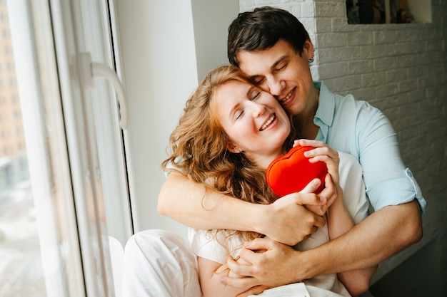 Couple in love watches a gift heart box on Valentine's day holiday.