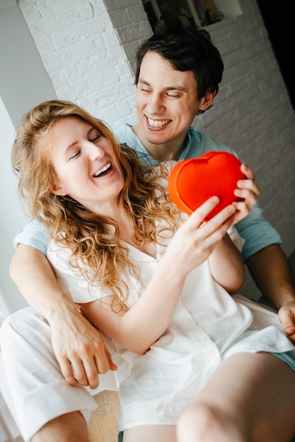 Couple in love watches a gift heart box on Valentine's day holiday.