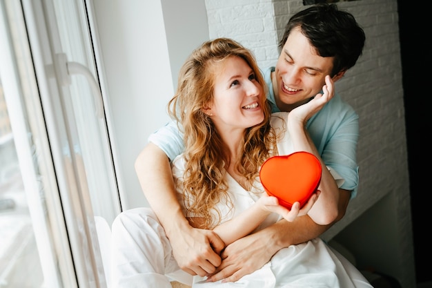 Couple in love watches a gift heart box on Valentine's day holiday.