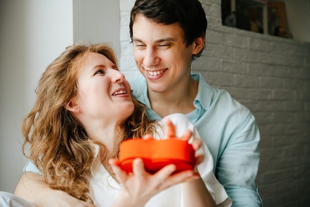 Couple in love watches a gift heart box on Valentine's day holiday.