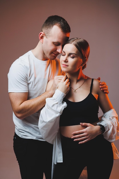 A couple in love in white shirts are hugging and enjoying each other A stylish couple embraces each other on a white background Happy family concept