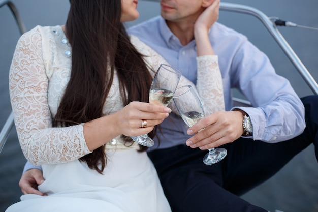 Couple in love with decorated wine glasses on wedding day.  Two glasses with champagne in bride and groom hands outdoors. Man and woman holds wine glasses close up. place of celebration.