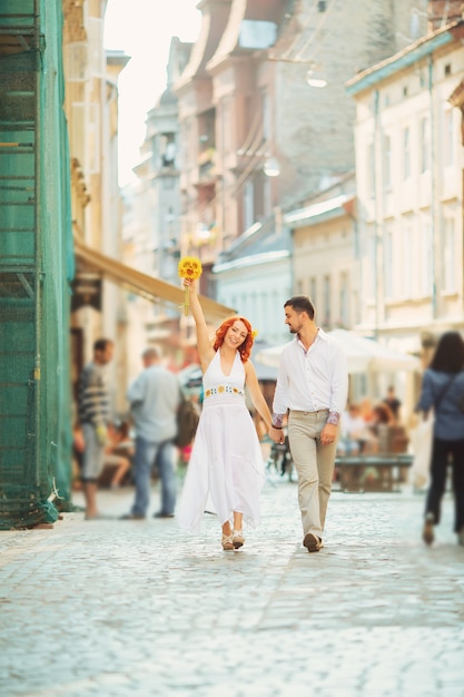 A couple of lovers people on the city walk. The love story of two young people. Man and woman embracing each other. Walking through the city summer day. Feelings of love between two people. Love story.