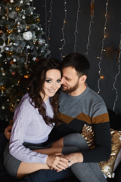 Couple of lovers posing near the Christmas tree