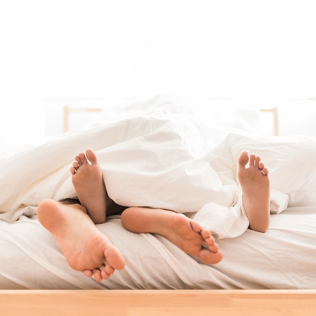 Couple lying barefoot on bed