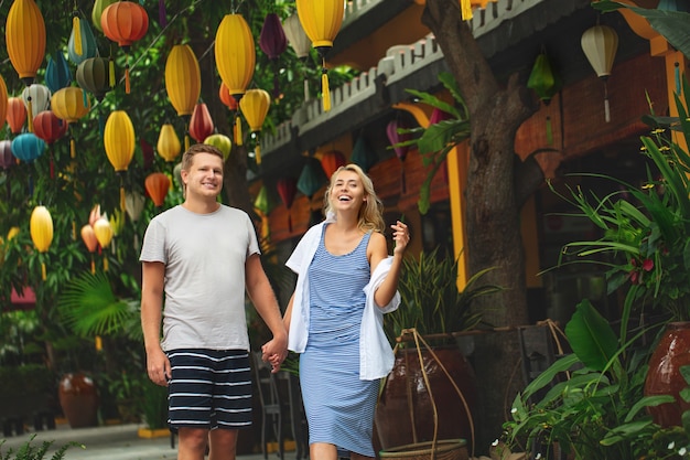 Couple a man and a woman travel together through the streets of an Asian city happy and beautiful