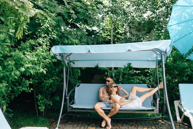 Couple man and woman on vacation having a rest on a swing on a tropical beach island The newlyweds in love spend the summer time together traveler