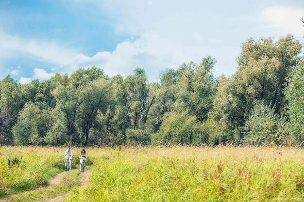 Couple man and woman in wedding style with bikes in nature happy