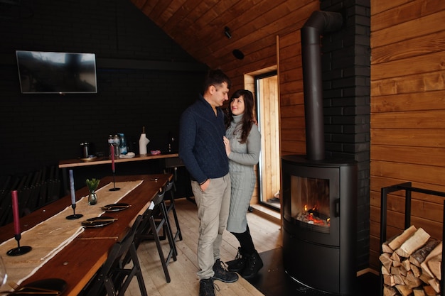 Couple in modern wooden house spending time together near fireplace in warm and love