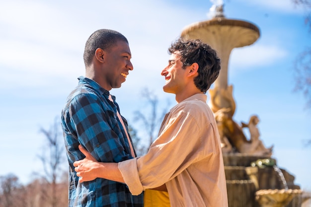 Couple of multiethnic men in a city fountain lgbt concept in a romantic pose looking at each other smiling