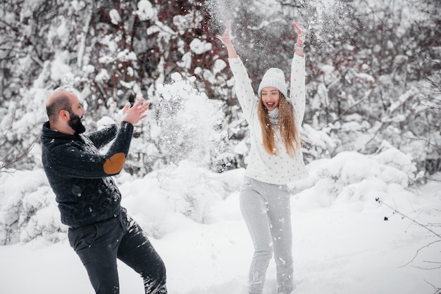 Couple playing with snow in the forest