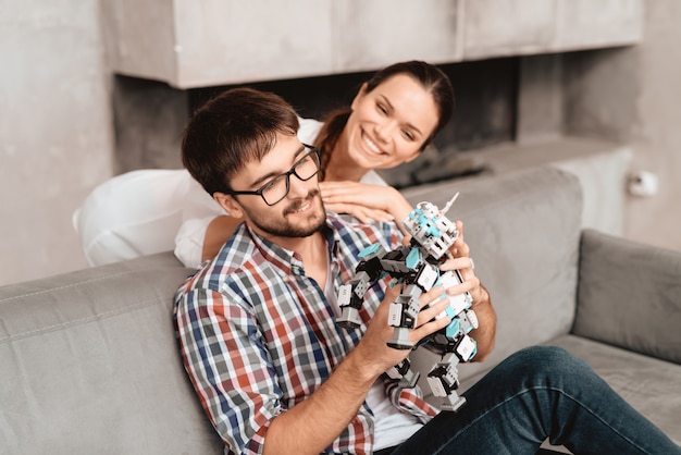 The couple plays with the robot a rhinoceros.