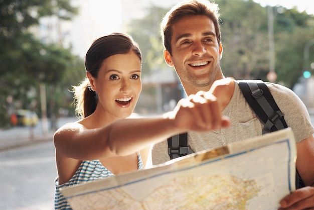 Couple pointing or map for tourist destination with direction tour route and excited on holiday and vacation in Brazil Face man and woman with smile in city street for explore tourism and travel