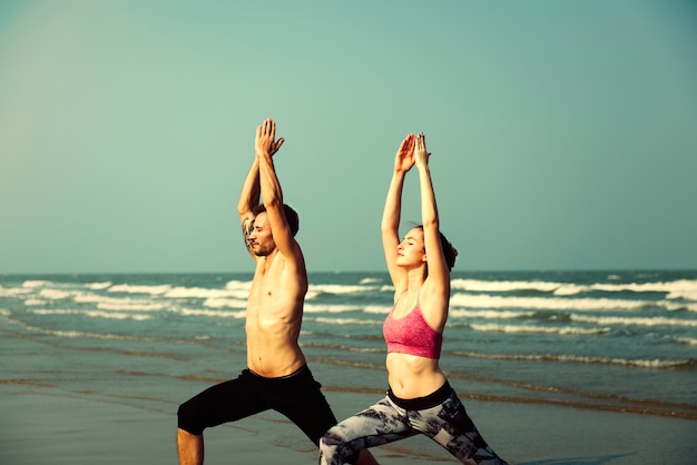 Couple practicing yoga at the beach