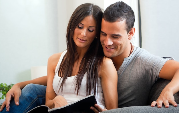 Couple reading magazine while sitting on sofa