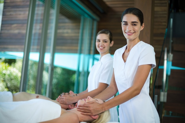 Couple receiving a face massage from masseur 