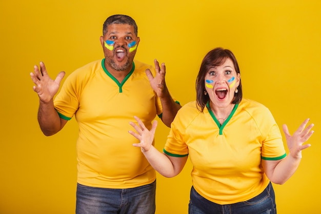 Couple redhaired woman and black man Brazilian soccer fans surprised wow incredible unbelievable