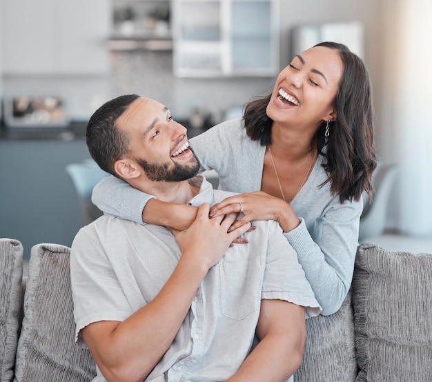 Couple relax on sofa laugh and smile together with love support and hug partner in living room of modern apartment home Black woman happy man and peace in lounge with wellness bonding on a couch