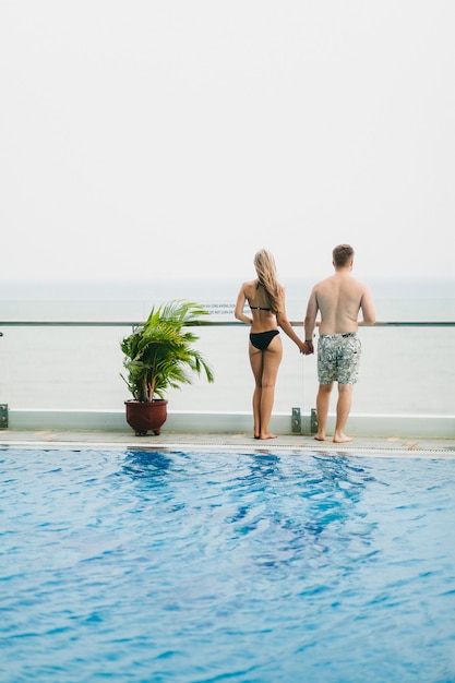 Couple relax in swimming pool. Back view