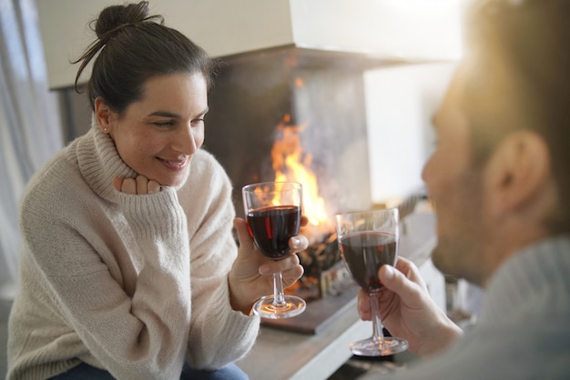  Couple relaxing by the fire enjoying glass of red wine                                          