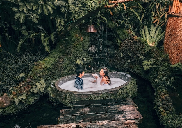 Couple relaxing in outdoor bath with tropical jungle  luxury spa hotel, lifestyle