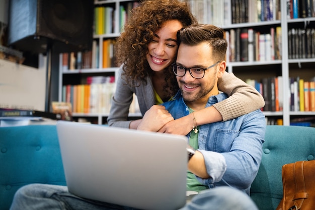 Couple relaxing together in sofa with computer pc having fun. Romantic young happy multiracial couple in love