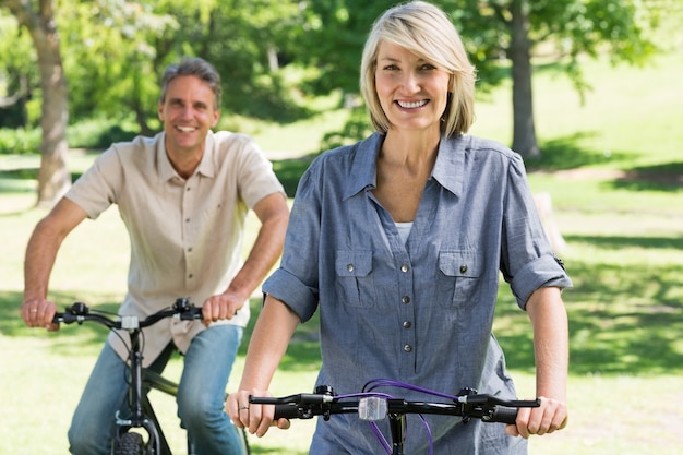 Couple riding bicycles in park