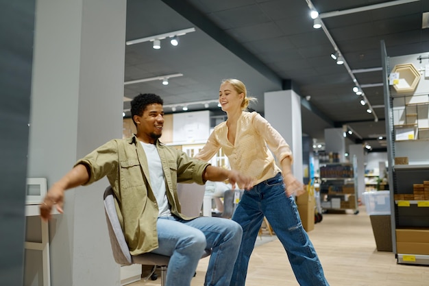 Couple riding on chair in furniture store