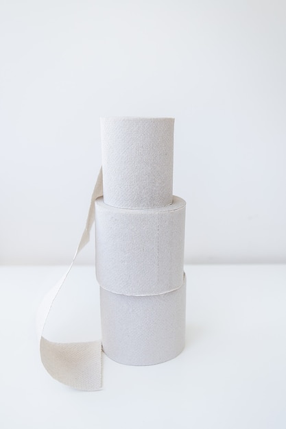 A couple of rolls of gray toilet paper are standing on a white table. Hygiene and cleanliness concept.