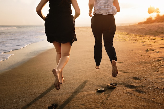 Couple running on the beach at sunset