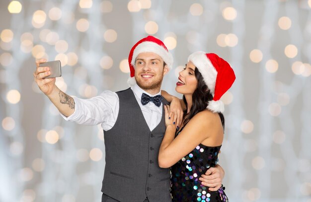 Photo couple in santa hats taking selfie at christmas