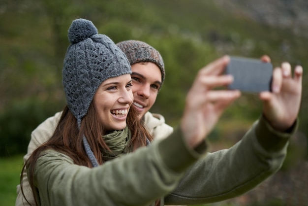 Photo couple selfie and smile while hiking in nature smartphone and capture moment in outdoors people happy and picture for memory and exploring wilderness trekking and photograph for social media