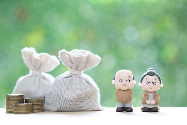 couple senior and gold coin money in the bag on natural green background