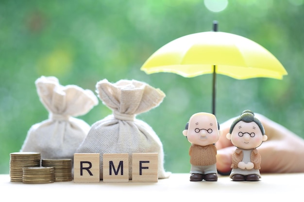 couple senior and hand holding the umbrella with stack of coins money on natural green background