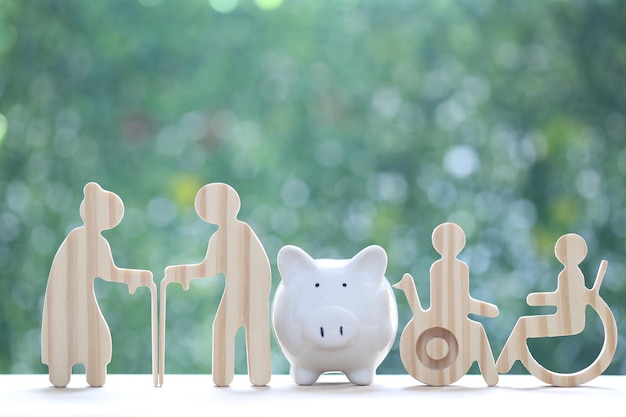 couple senior and wheelchair user with spiggy bank on natural green background