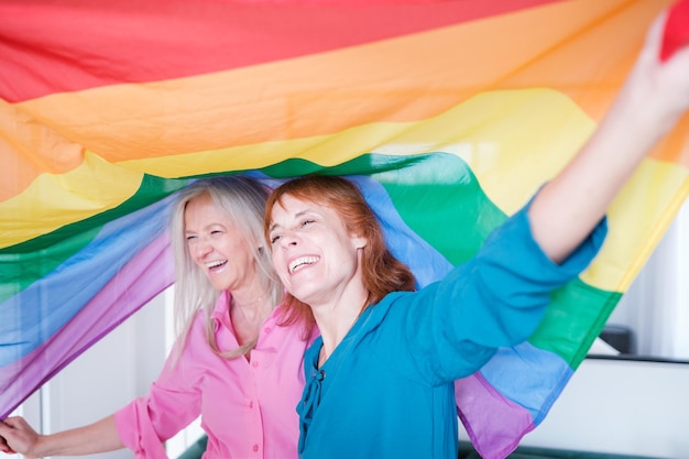 Couple of senior women wrapped in a lgtbi pride flag Concept pride love share