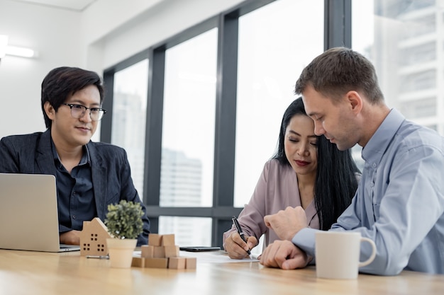 Couple signed the house purchase contract with the house sales agents. Buy or sell home concept. Happy couple in transaction signing contract of house with broker.