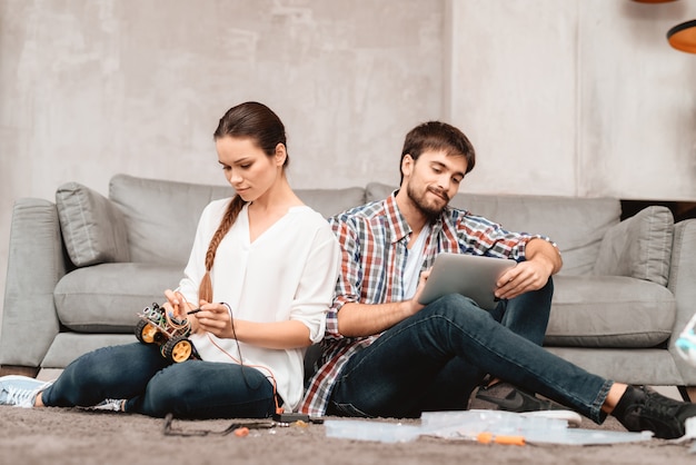 Couple Sit on Floor. Work Together with Robotics.