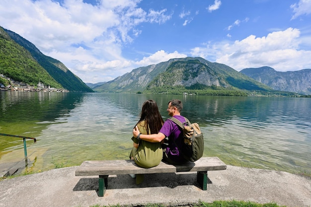 Couple sitting on bench over Austrian alps lake in Hallstatt Salzkammergut Austria