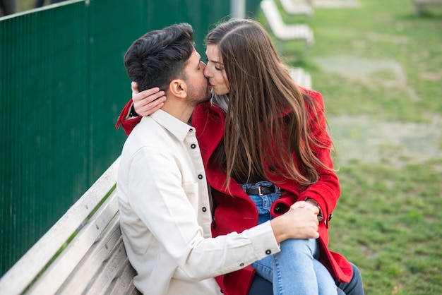 Couple sitting on a bench outdoors and kissing