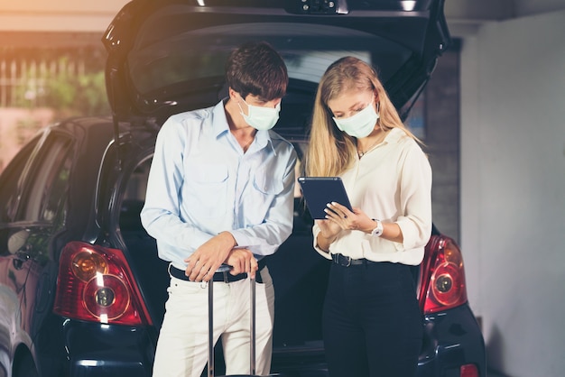 couple sitting beside car with mask