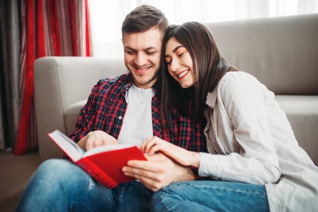 Couple sitting on floor and looks at book together