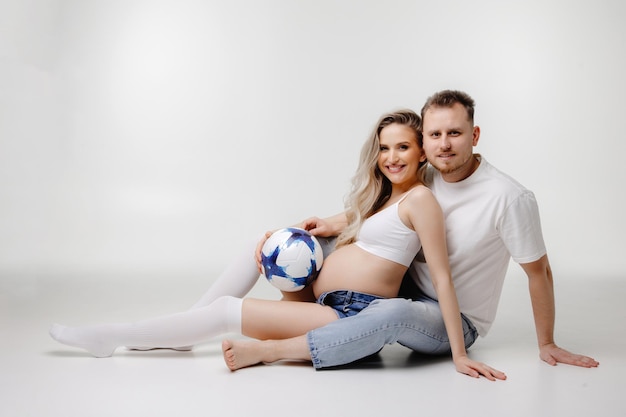 couple sitting on the floor pregnant woman with her husband sitting on a white background