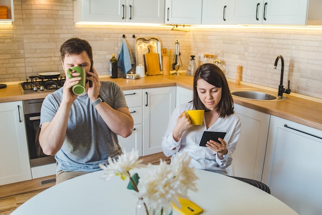 Couple sitting at the kitchen in the morning drinking tea reading news