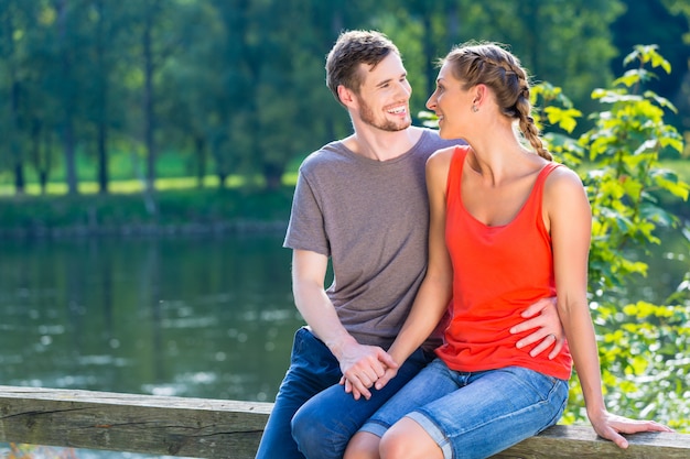 Couple sitting at riverbank in summer