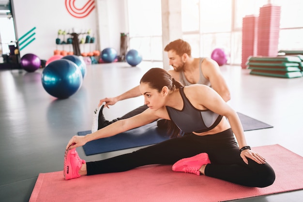 couple sitting on the sports carpet together and stretching