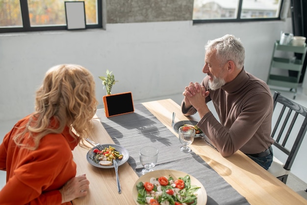 A couple sitting at the table and watching something online