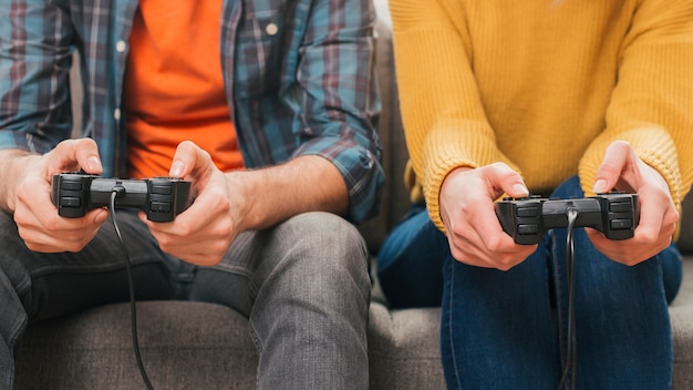 Couple sitting together on sofa playing the video game with joystick