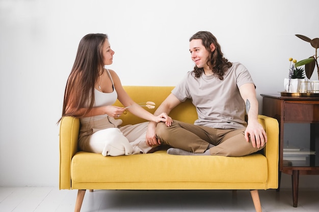 Couple sitting on yellow sofa in the room Man and woman in love in a new apartment Home comfort