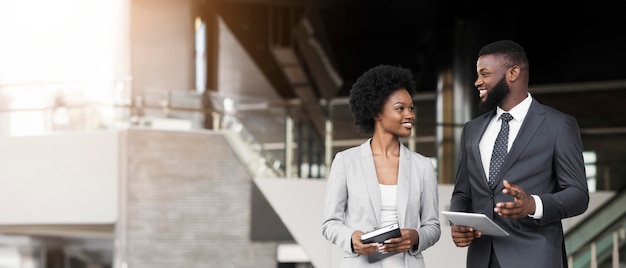 Couple of smiling african american employees friendly chatting outdoors copy space